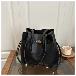 Detail of a black bucket bag showing the golden twist lock on textured leather