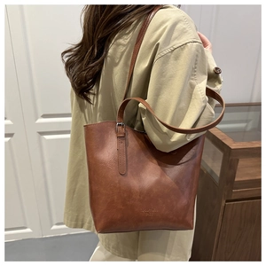 Brown faux leather tote bag detail with long shoulder strap and metallic buckle accents