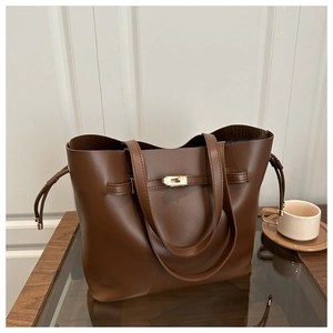 Close-up of brown bucket bag showing the golden lock detail and premium leather texture