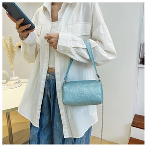 Détail du sac cylindre à paillettes bleu clair avec chaîne argentée porté par le mannequin