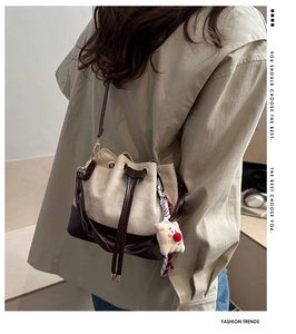 Detail of drawstring bucket bag with suede texture and plaid ribbon on a model