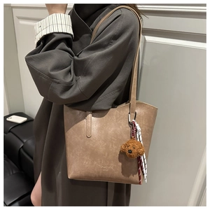 Détail du sac cabas kaki avec pendentif chien en peluche et logo de marque
