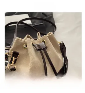 Detail of suede bucket bag with drawstring closure, leather trim and striped scarf accent