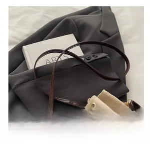 Detail of beige suede bucket bag with drawstring closure and brown leather shoulder strap
