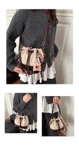 Detail of drawstring bucket bag with beige matte texture and brown leather trim accents