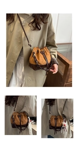 Detail of vintage suede bucket bag with drawstring closure and cute bear pendant