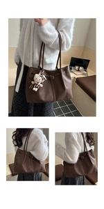 Detail of dark brown tote bag featuring vintage belt buckle and leopard cat charm