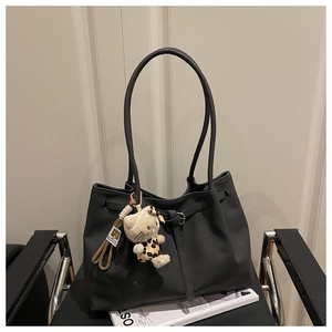 Detail of black tote bag on chair featuring a stylish leopard-print kitten doll charm