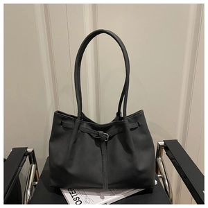 Detail of black matte leather tote bag with drawstring texture and long slim shoulder strap