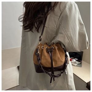 Detail of a color-block bucket bag with suede texture, drawstring closure and logo