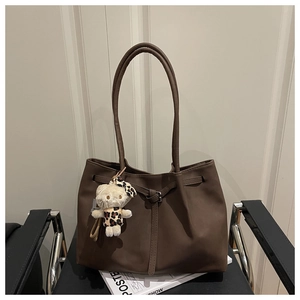 Close-up of a large brown tote bag with leather straps and a leopard print plush charm