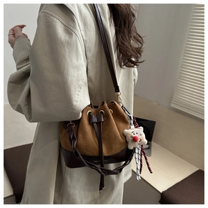 Detail view of a vintage drawstring bucket bag with contrast stitching and bear charm