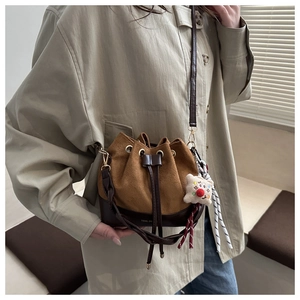 Detail of vintage suede bucket bag with drawstring closure and plush pendant charm