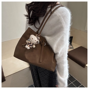 Detail view of large brown suede tote bag with leopard print Hello Kitty plush charm