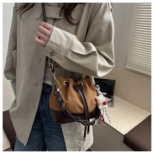 Detail of drawstring bucket bag in caramel suede with plush bear charm and gold hardware