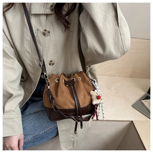 Detail of suede bucket bag with drawstring closure and decorative biscuit charm