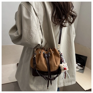 Detail of drawstring bucket bag with suede texture and cute plush toy charm on long strap