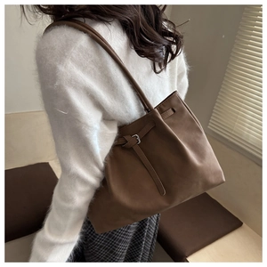 Close-up of a dark brown pleated tote bag in matte faux leather with silver buckle detail