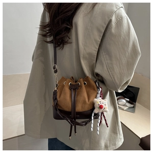 Brown suede bucket bag with drawstring closure and cute plush bear charm on model