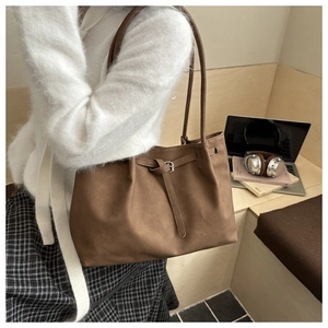 Close-up of a brown tote bag with matte synthetic leather and stylish buckle straps