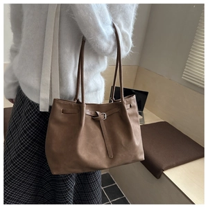 Brown large capacity leather tote bag with decorative buckle details shown on shoulder
