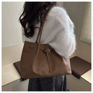 Detail of vintage brown tote bag featuring decorative buckle and matte faux leather texture