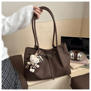 Close-up of large dark brown tote bag with cute plush doll charm and double straps