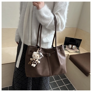 Detail of dark brown tote bag with pleated texture and stylish plush charm decoration