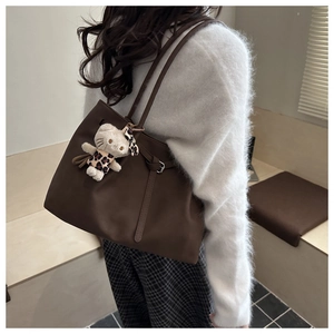 Detail of coffee brown tote bag with drawstring texture and plush character pendant