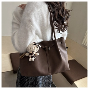 Detail view of large dark brown tote bag with matte leather finish and plush bunny charm