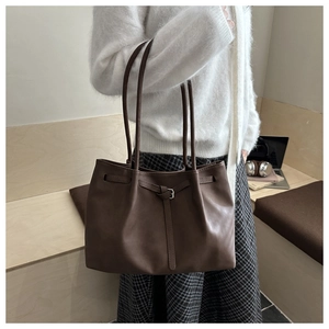 Detail of dark coffee leather tote bag with silver buckle drawstring and pleated texture