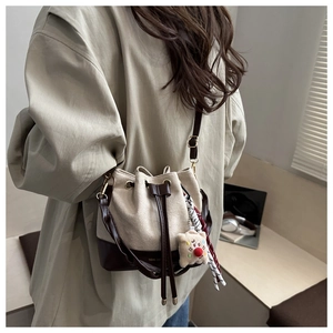 Detail of drawstring bucket bag with contrast leather trim and star charm on a shoulder strap