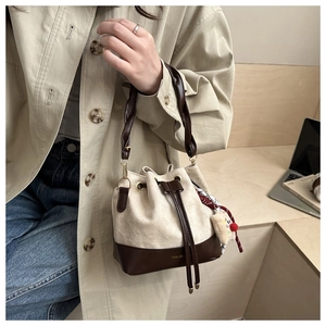 Detailed view of vintage beige bucket bag with teddy charm and brown leather base