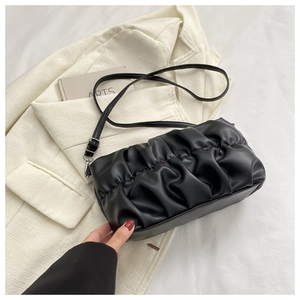 Detail of black pleated cloud bag with adjustable strap on white background