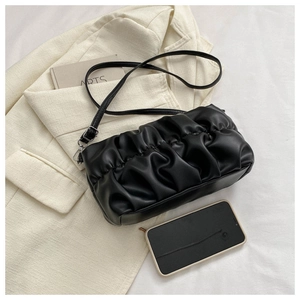 Detailed view of black pleated cloud bag with adjustable strap and smartphone for size