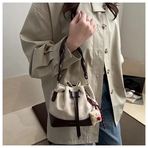 Detail of drawstring bucket bag with woven handle and plush bear charm decoration
