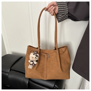 Close-up of vintage brown tote bag featuring a cute character plush pendant