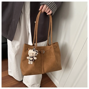Close-up of brown suede tote bag with drawstring detail and cute plush cat charm