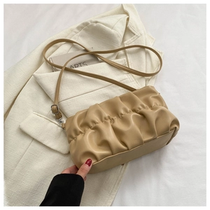 Close-up of pleated khaki cloud bag made of faux leather on white fabric background