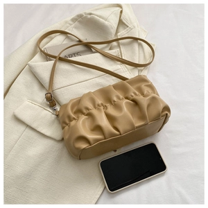 Detail of khaki pleated cloud bag with adjustable strap and zipper on white blazer