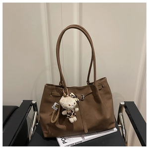 Detail of vintage coffee tote bag with silver buckle and leopard plush kitten charm