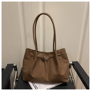 Macro detail of brown matte leather tote bag featuring sleek metal buckle and long handles