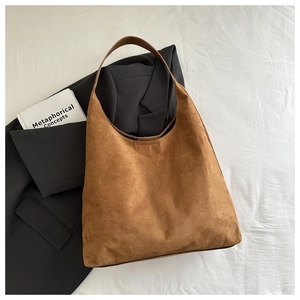 Gros plan sur un sac cabas en daim marron avec blazer et magazine pour un look chic urbain