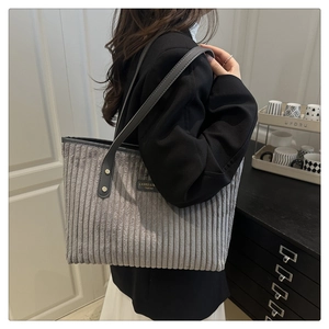 Dettaglio della borsa tote in velluto a coste grigio con trama verticale e tracolla in pelle