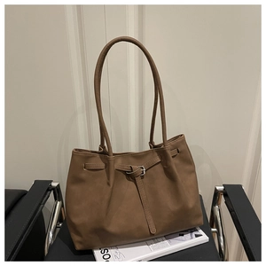 Detail of a large vintage brown tote bag with metal buckle on a stylish chair