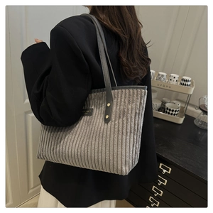 Detail of grey corduroy tote bag showing vertical texture and black leather straps