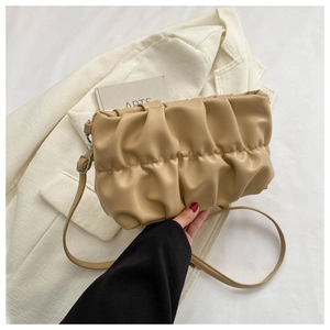 Detail of beige pleated cloud bag with soft faux leather texture and adjustable strap