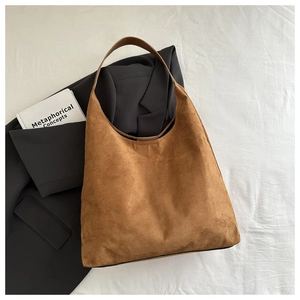Sac fourre-tout hobo en daim marron sur tissu blanc avec un style de travail minimaliste