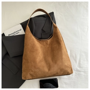 Gros plan d'un sac cabas en daim marron sur un blazer avec une texture mate haut de gamme