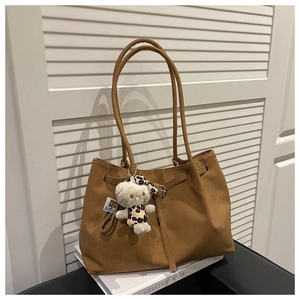 Detailed view of brown tote bag with pleated drawstring and plush cat pendant charm